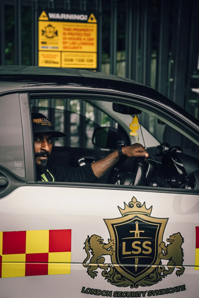 Security officer in a marked patrol vehicle outside a commercial property.