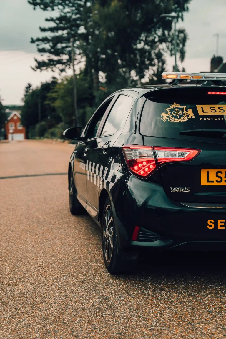LSS security patrol vehicle with warning lights parked on a residential driveway.
